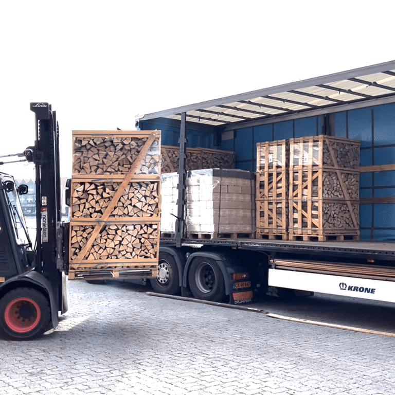Forklift loading firewood crates and wood fuel pallets onto delivery truck